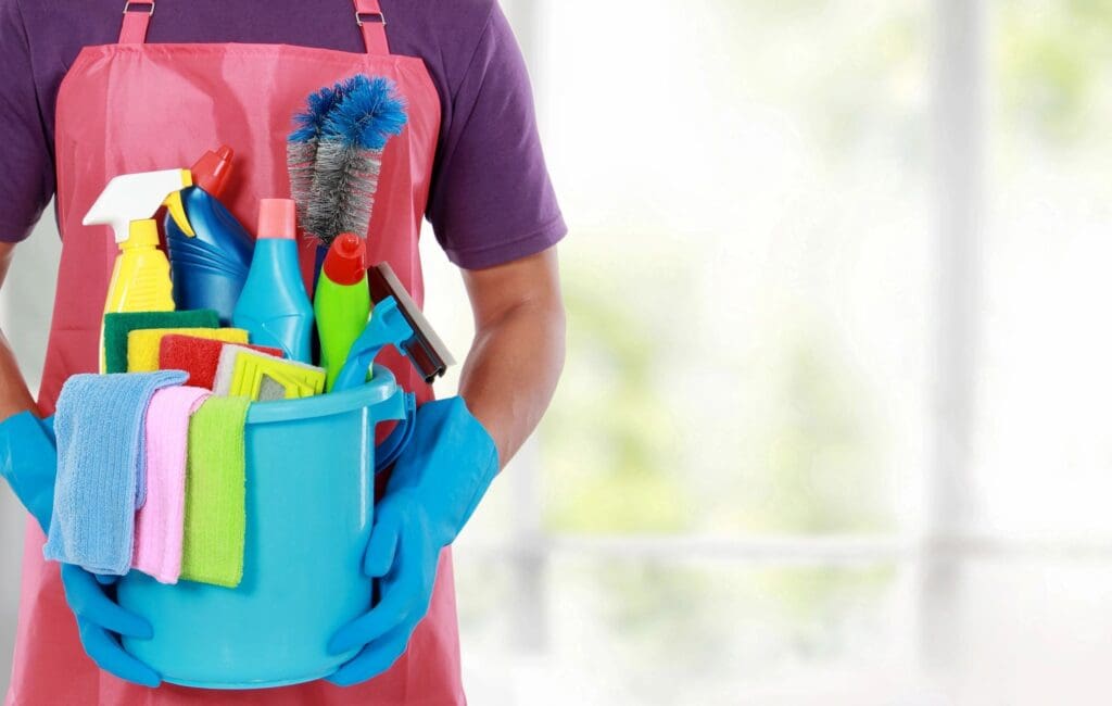 a person holding a bucket with cleaning products